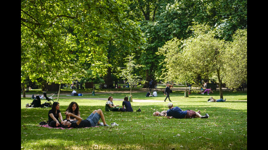 People sit on the grass in St James's park, in London, Tuesday, June 25, 2024, as the temperatures are set to reach 28C during the week. (AP Photo/Alberto Pezzali) (AP)