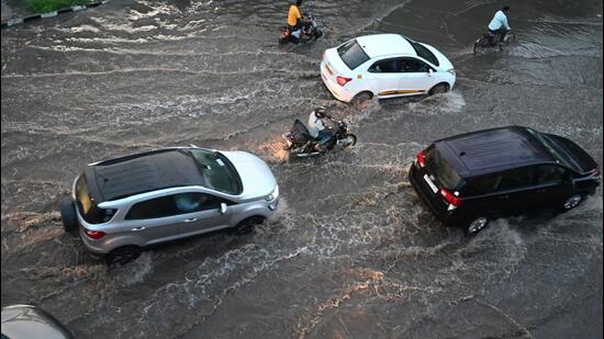 Vehicles plow through a waterlogged stretch of National Highway 48 in Gurugram on Saturday. (Parveen Kumar/HT Photo)