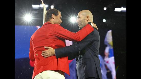 Torchbearer Zinedine Zidane passes the Olympic torch to Rafael Nadal of Spain during the opening ceremony. (AFP)