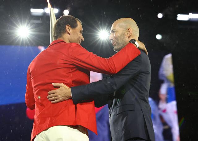 Torchbearer Zinedine Zidane passes the Olympic torch to Rafael Nadal of Spain during the opening ceremony. (AFP) Torchbearer Zinedine Zidane passes the Olympic torch to Rafael Nadal of Spain during the opening ceremony. (AFP)