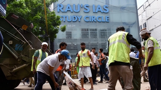 UPSC aspirants death news LIVE: Delhi Municipal Corporation workers outside the 'Rao IAS Study Centre' during the students' protest after three civil service aspirants died due to flooding in the basement of the coaching centre, at Old Rajinder Nagar in New Delhi on Sunday.