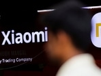 A man walks past a logo of Xiaomi, a Chinese manufacturer of consumer electronics, outside a shop.
