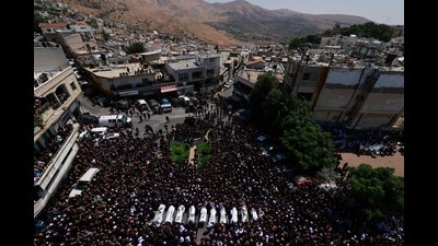 TOPSHOT - Druze elders and mourners surround the coffins of 10 of the 12 people killed in a rocket strike from Lebanon a day earlier, during a mass funeral in the Druze town of Majdal Shams in the Israel-annexed Golan Heights, on July 28, 2024. (Photo by Menahem Kahana / AFP) (AFP) TOPSHOT - Druze elders and mourners surround the coffins of 10 of the 12 people killed in a rocket strike from Lebanon a day earlier, during a mass funeral in the Druze town of Majdal Shams in the Israel-annexed Golan Heights, on July 28, 2024. (Photo by Menahem Kahana / AFP) (AFP)