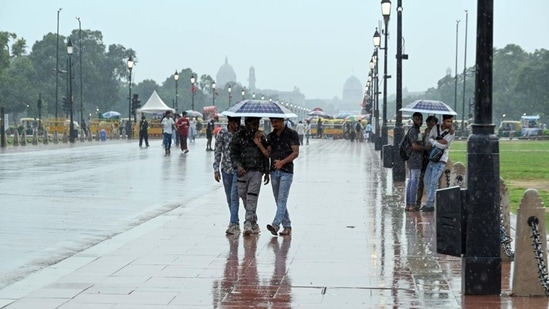 Visitors at Kartavya Path, New Delhi face light rain on Tuesday as high humidity makes Delhi swelter. (Sanjeev Verma/HT Photo)
