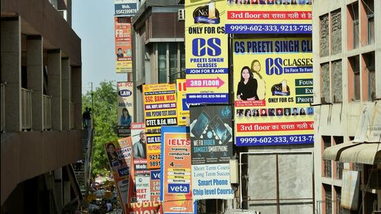 People walk past boards of coaching centres in Laxmi Nagar. (Amal K/HT Photo)