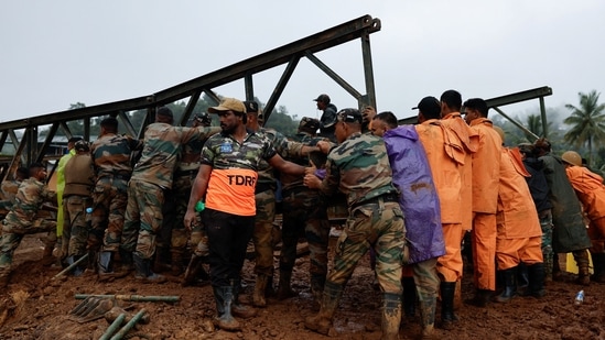 Army personnel and volunteers lift a portion of a bridge during its re-construction, after landslides hit Chooralmala in Wayanad district.(Reuters)