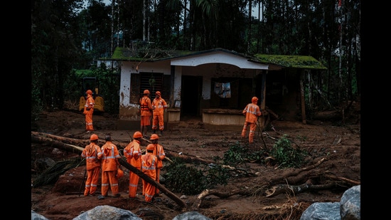 Rescuers stand next to a damaged house as they search through mud and debris for a third day after landslides set off by torrential rains in Wayanad district, on Thursday. (AP)