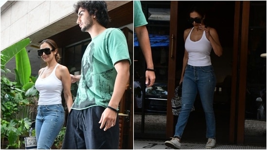 Malaika Arora embraced the classic white tee and blue denim jeans combination for an outing with her son, Arhaan Khan. She wore a bodycon tank top and fitted jeans, styled with sneakers, futuristic sunnies, a centre-parted messy bun, and a no-makeup look. (HT Photo/Varinder Chawla)