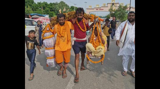 With water-filled utensils weighing 53 kg on one side and their mother Jalwati of the same weight seated on the other side of the kanwar slung across their shoulders, the three brothers walked for 10 km every day. (HT Photo)