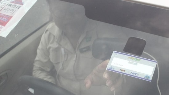 FASTag KYC rules: A man points to the FASTag on his vehicle's windshield, at the toll office at Kherki-Daula toll plaza, in Gurugram.