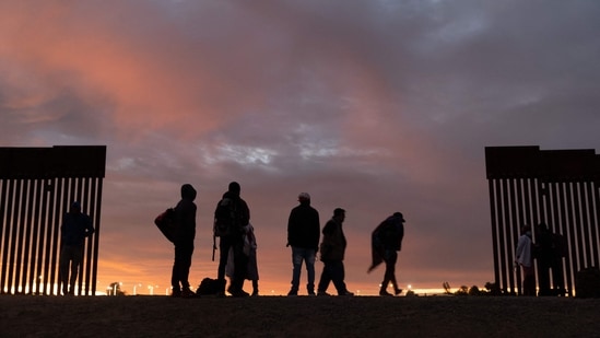 (FILES) Expectant parents from Haiti stand at a gap in the U.S.-Mexico border wall after traveling from South America to the United States, in Yuma, Arizona, December 10, 2021. (AFP)