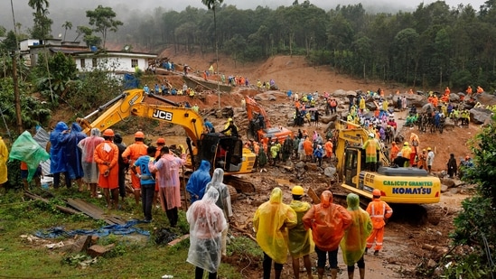 People watch as search operations are carried out after landslides hit Mundakkai village in Wayanad district in Kerala,