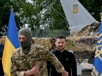 TOPSHOT - Ukraine's President Volodymyr Zelensky (C/R) stands in front of a pair of F16 fighter jets after giving an award to a Ukranian fighter pilot during Ukrainian Air Forces Day at an undisclosed location on August 4, 2024. (Photo by Sergei SUPINSKY / AFP)