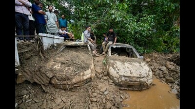 People gather near damaged vehicles following a cloudburst, in Ganderbal district, on Sunday. A cloudburst in the district of Jammu and Kashmir has damaged a road, leading to the closing of the arterial Srinagar-Leh national highway, officials said on Sunday. (PTI)