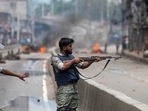 Bangladesh crisis: A policeman aims his weapon at protesters during a curfew imposed following violence during protests against Prime Minister Sheikh Hasina and her government, in Dhaka, Bangladesh.