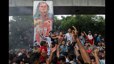 Protesters celebrate beside a defaced portrait of Prime Minister Sheikh Hasina after news of her resignation, in Dhaka, Bangladesh. (AP)