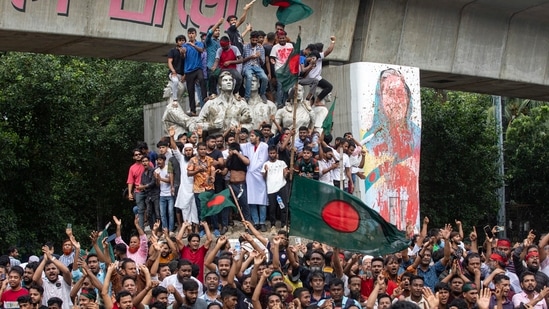 Protesters climb a public monument as they celebrate after getting the news of Prime Minister Sheikh Hasina's resignation in Dhaka, Bangladesh, (AP)