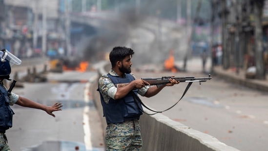 Bangladesh crisis: A policeman aims his weapon at protesters during a curfew imposed following violence during protests against Prime Minister Sheikh Hasina and her government, in Dhaka, Bangladesh.(AP)