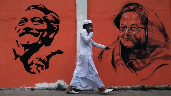  In this photo taken on December 16, 2018 a man walks past a wall with images of Bangladeshi founding father Sheikh Mujibur Rahman (L) and Sheikh Hasina Wazed (R) (Photo by REHMAN ASAD / AFP)(AFP)