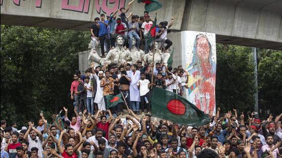 Protesters climb a public monument as they celebrate the news of Prime Minister Sheikh Hasina's resignation, in Dhaka, Bangladesh, on Monday. (AP)