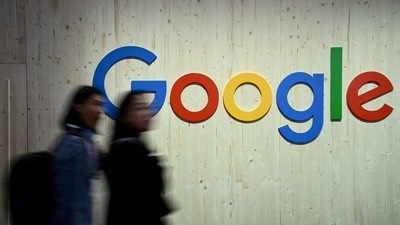 People walk next to a Google logo during a trade fair. (Reuters)