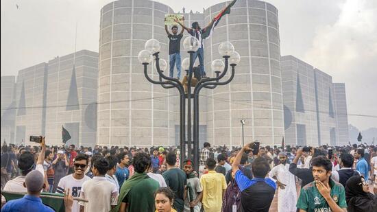 Anti-government protesters celebrate outside the Bangladesh Parliament after getting the news of Prime Minister Sheikh Hasina's resignation, in Dhaka, Bangladesh, on Monday (AP)