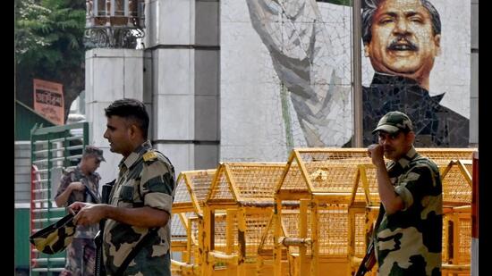 Border Security Force (BSF) personnel walk past a mural of Sheikh Mujibur Rahman, Bangladesh's founding father and parent of the country's ousted Prime Minister Sheikh Hasina at the India-Bangladesh border of Petrapole about 100km north east of Kolkata on August 6, 2024. (Photo by Dibyangshu SARKAR / AFP) (AFP)