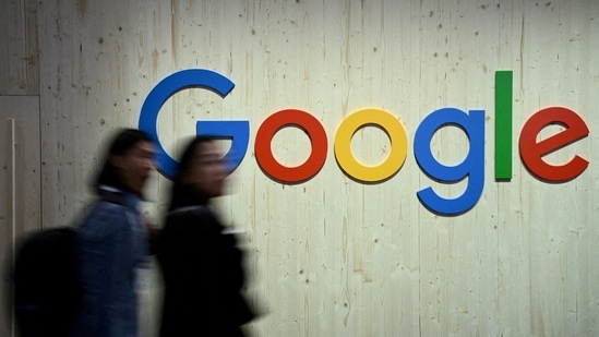 People walk next to a Google logo during a trade fair.(Reuters)