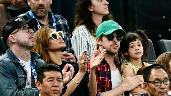 La actriz estadounidense Eva Mendes (CL) y su pareja, el actor canadiense Ryan Gosling (CR), asisten a la final femenina de barras asimétricas de gimnasia artística durante los Juegos Olímpicos de París 2024 en el Bercy Arena de París, el 4 de agosto de 2024. (Foto de Loic VENANCE / AFP)