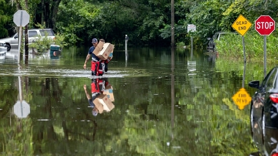 Savannah Fire Advanced Firefighters Andrew Stevenson, front, and Ron Strauss carry food to residents in the Tremont Park neighborhood that where stranded in flooding from Tropical Storm Debby, Tuesday, Aug. 6, 2024, in Savannah, Ga. (AP Photo/Stephen B. Morton)(AP)