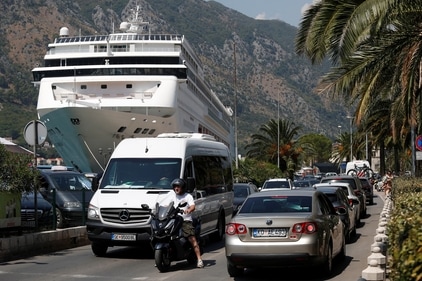 Vehicles move in a traffic jam in front of a cruise ship docked in front of Old Town amid concerns about 'over-tourism' in Kotor, Montenegro. (REUTERS)