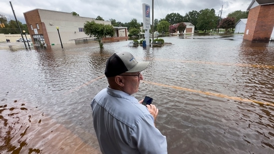 Randy Sikes speaks to his relatives on a mobile phone as he stands in residual rain water flooding the downtown area caused by Tropical Storm Debby, Thursday, Aug. 8, 2024, in Bladenboro, NC. (AP Photo/John Minchillo)(AP)