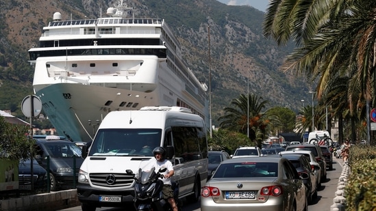 Vehicles move in a traffic jam in front of a cruise ship docked in front of Old Town amid concerns about 'over-tourism' in Kotor, Montenegro. (REUTERS)