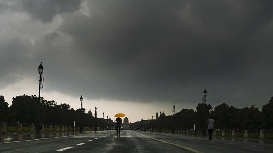 People caught in the rain at Kartavya Path, in New Delhi on Friday. (RAJ K RAJ /HT PHOTO)