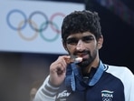 Bronze medallist Aman Sehrawat of India bites his medal.