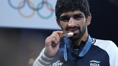 Bronze medallist Aman Sehrawat of India bites his medal. (REUTERS)