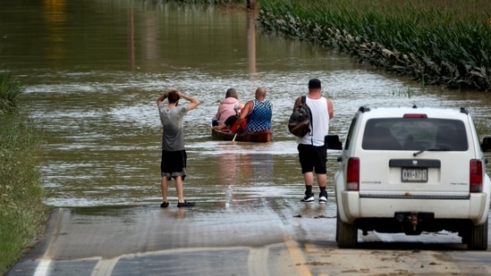 Eric Combs, Maverick Knight and Michelle Knight paddle away as they traverse high water along Canisteo River Road in Canisteo, N.Y., Friday, Aug. 9, 2024, after remnants of Tropical Storm Debby swept through the area. (AP Photo/Craig Ruttle)(AP)