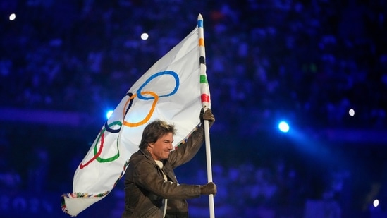 Tom Cruise carries the Olympic flag during the 2024 Summer Olympics closing ceremony at the Stade de France(AP)