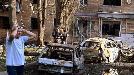 A man reacts while standing next to burnt-out remains of cars in the courtyard of a multi-storey residential building, which according to local authorities was hit by debris from a destroyed Ukrainian missile, in the course of Russia-Ukraine conflict in Kursk, Russia, on Sunday. (REUTERS)