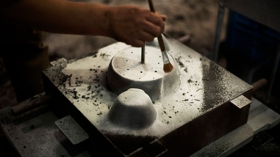 Craftsman Katsunori Suzuki uses a brush to bring up a contour of a cooking pot to make detailed designs as he makes a cast iron pot by hand at the Oigen foundry in Oshu, northeastern Japan.(AP Photo/Hiro Komae)