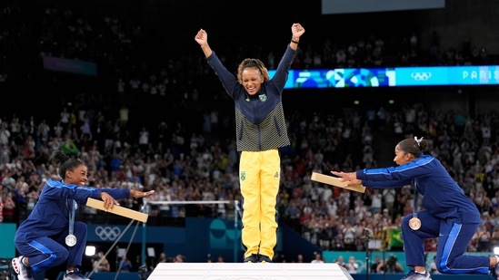 Silver medalist Simone Biles, of the United States, left, and bronze medalist Jordan Chiles, of the United States, right, bow to gold medalist Rebeca Andrade, of Brazil, during the medal ceremony for the women's artistic gymnastics.(AP) Silver medalist Simone Biles, of the United States, left, and bronze medalist Jordan Chiles, of the United States, right, bow to gold medalist Rebeca Andrade, of Brazil, during the medal ceremony for the women's artistic gymnastics.(AP)