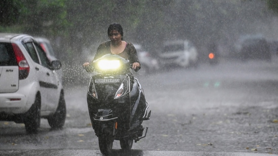 Commuters step out during evening rain at sector 12, in Noida, India, on Sunday, August 04, 2024. (Photo by Sunil Ghosh / Hindustan Times) 