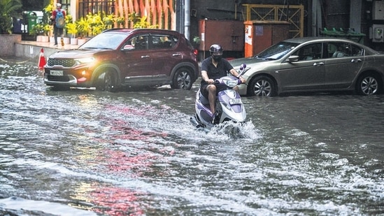 A commuter wades through a waterlogged road after rain, at New Friends Colony in New Delhi. (RAJ K RAJ /HT PHOTO)