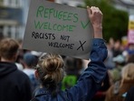 A protester holds a placard during a counter demonstration against an anti-immigration protest called by far-right activists, outside the Asylum Welcome immigration support service offices in Oxford, western England on August 7, 2024. (Photo by JUSTIN TALLIS / AFP) A protester holds a placard during a counter demonstration against an anti-immigration protest called by far-right activists, outside the Asylum Welcome immigration support service offices in Oxford, western England on August 7, 2024. (Photo by JUSTIN TALLIS / AFP)