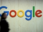 People walk next to a Google logo during a trade fair.