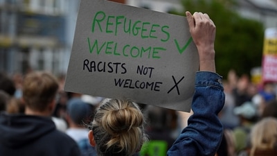 A protester holds a placard during a counter demonstration against an anti-immigration protest called by far-right activists, outside the Asylum Welcome immigration support service offices in Oxford, western England on August 7, 2024. (Photo by JUSTIN TALLIS / AFP) A protester holds a placard during a counter demonstration against an anti-immigration protest called by far-right activists, outside the Asylum Welcome immigration support service offices in Oxford, western England on August 7, 2024. (Photo by JUSTIN TALLIS / AFP)
