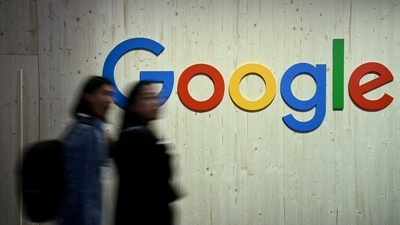 People walk next to a Google logo during a trade fair. (Reuters)