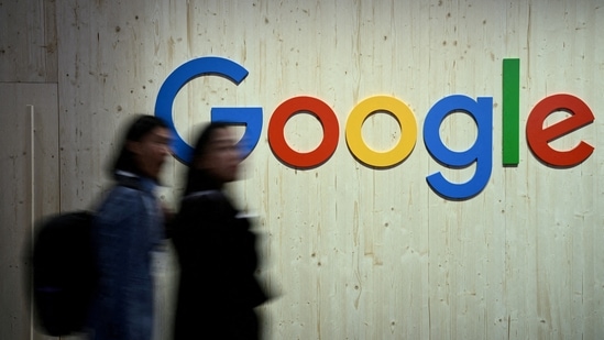 People walk next to a Google logo during a trade fair.(Reuters)