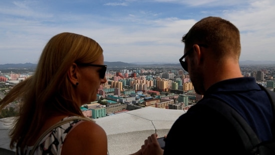 Foreign tourists take photos of the city skyline from the viewing deck at Juche Tower in Pyongyang, North Korea. Picture taken September 11, 2018. North Korea to open border for foreign tourists in December 2024, tour operators say (REUTERS/Danish Siddiqui/File Photo)