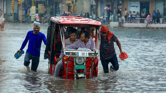 A vehicle moves through a waterlogged Sikar road following heavy monsoon rain in Jaipur on Monday. (PTI)(HT_PRINT)